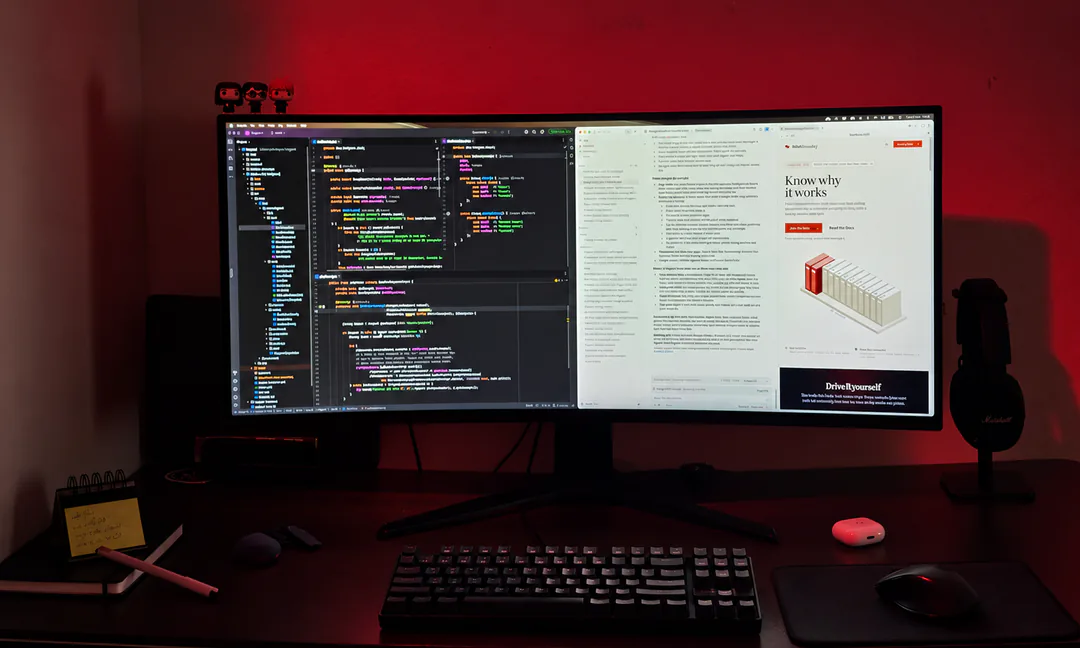 My desk in Pro mode: one ultrawide monitor with code on one side and the running app on the other, lit red